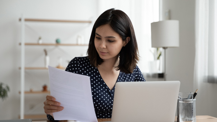 Confident asian woman work on computer considering paperwork